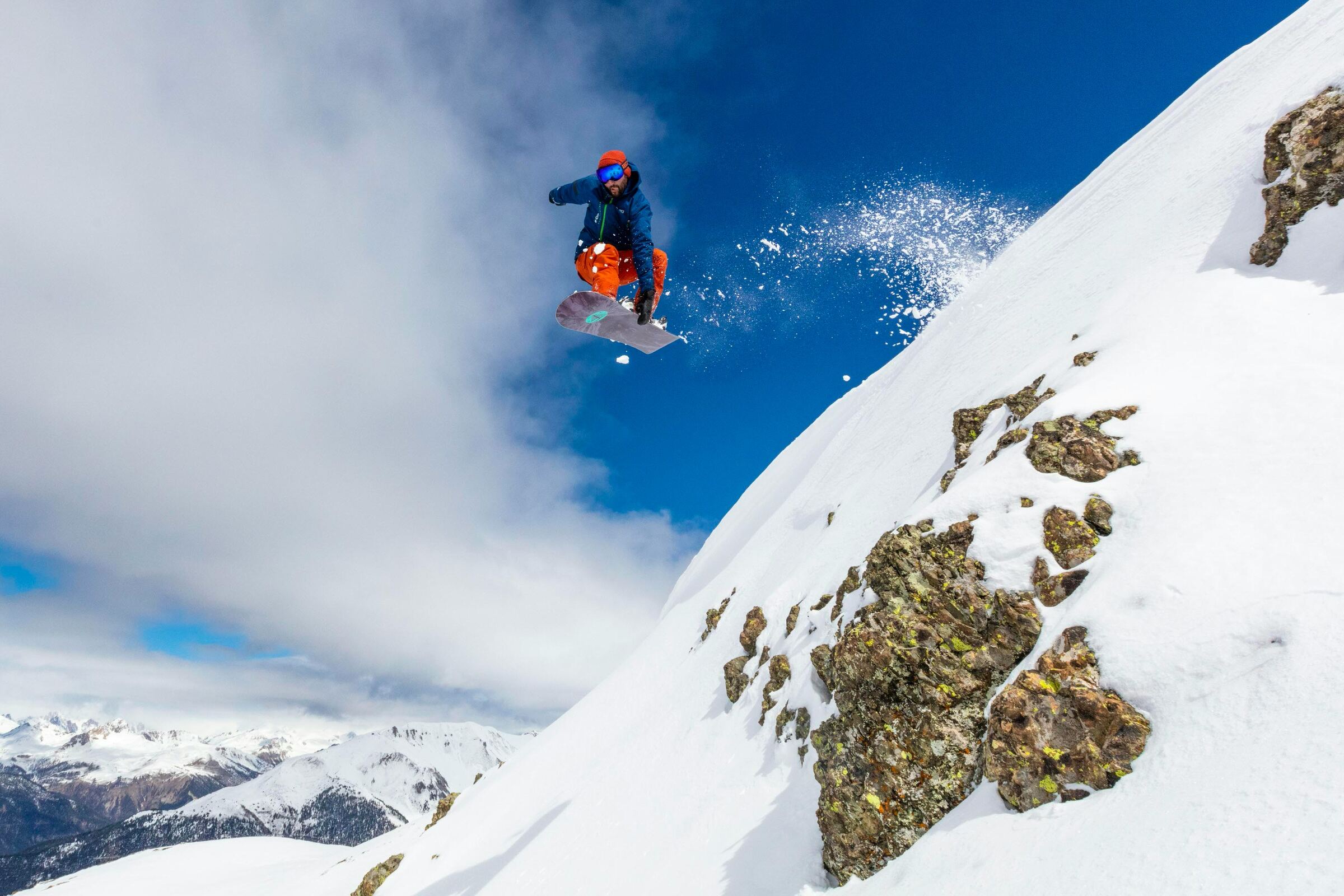 A skier committed mid-air above an alpine ridge — calculated risk, executed.