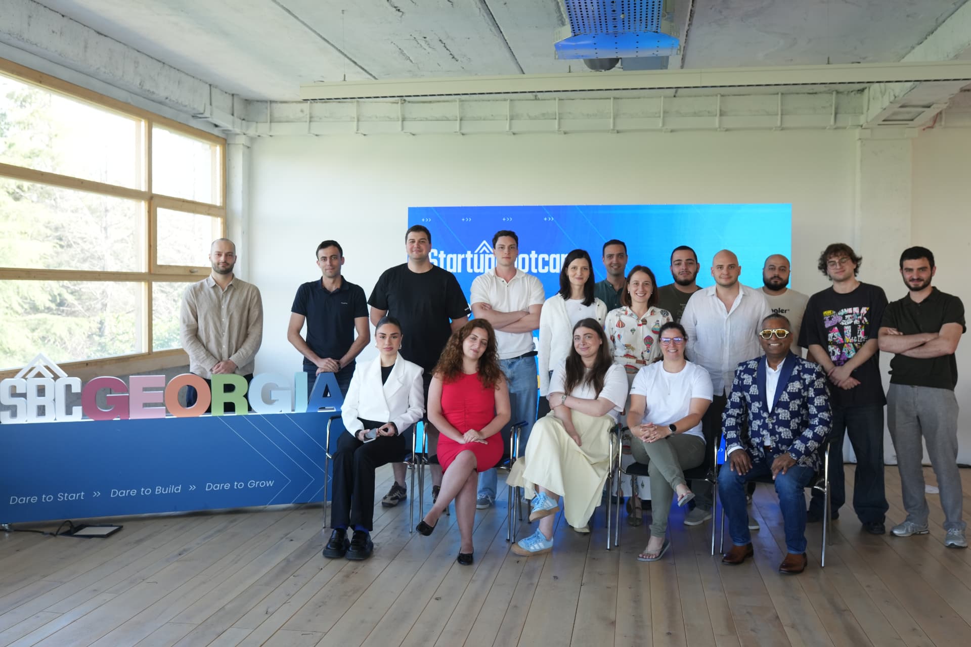 The 2026 Dare to Grow cohort beside the SBC Georgia sign and a Startupbootcamp screen